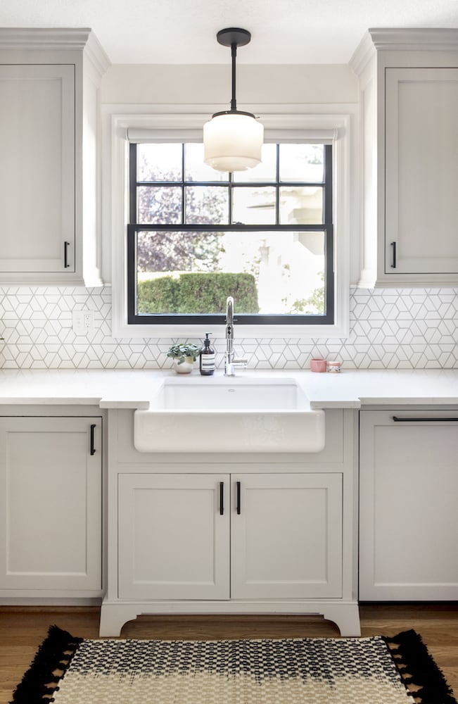 Straight-on look at kitchen apron sink, black deco ceiling light sconce, window