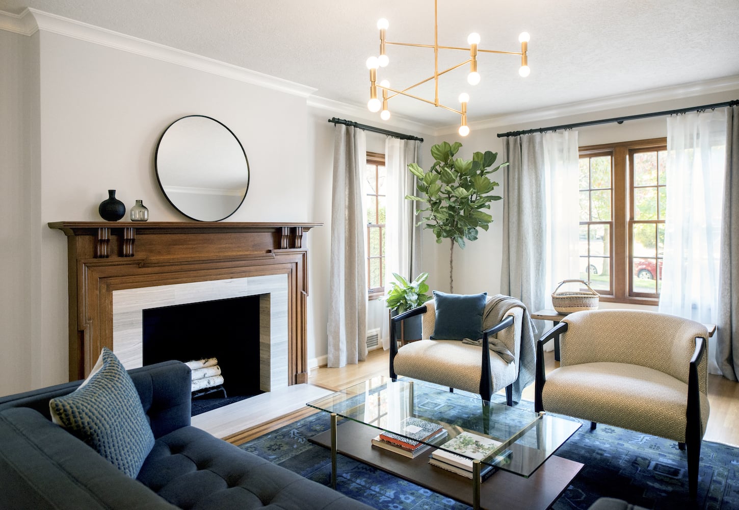 Living room with original traditional wood fireplace trim, modern gold chandelier