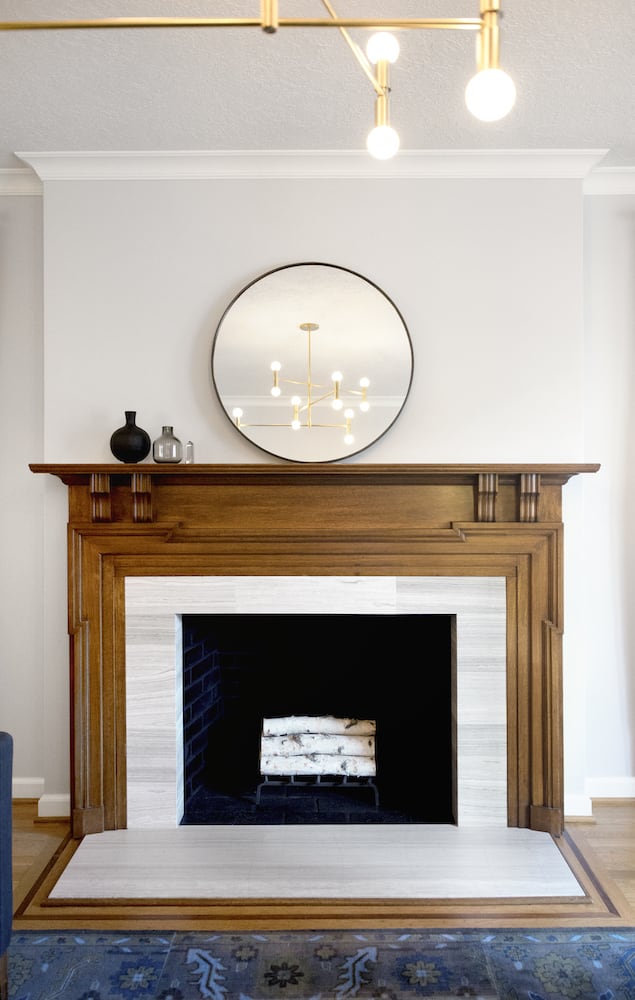 Incredible modern fireplace wood trim detail, blue rug, white marble and mirror