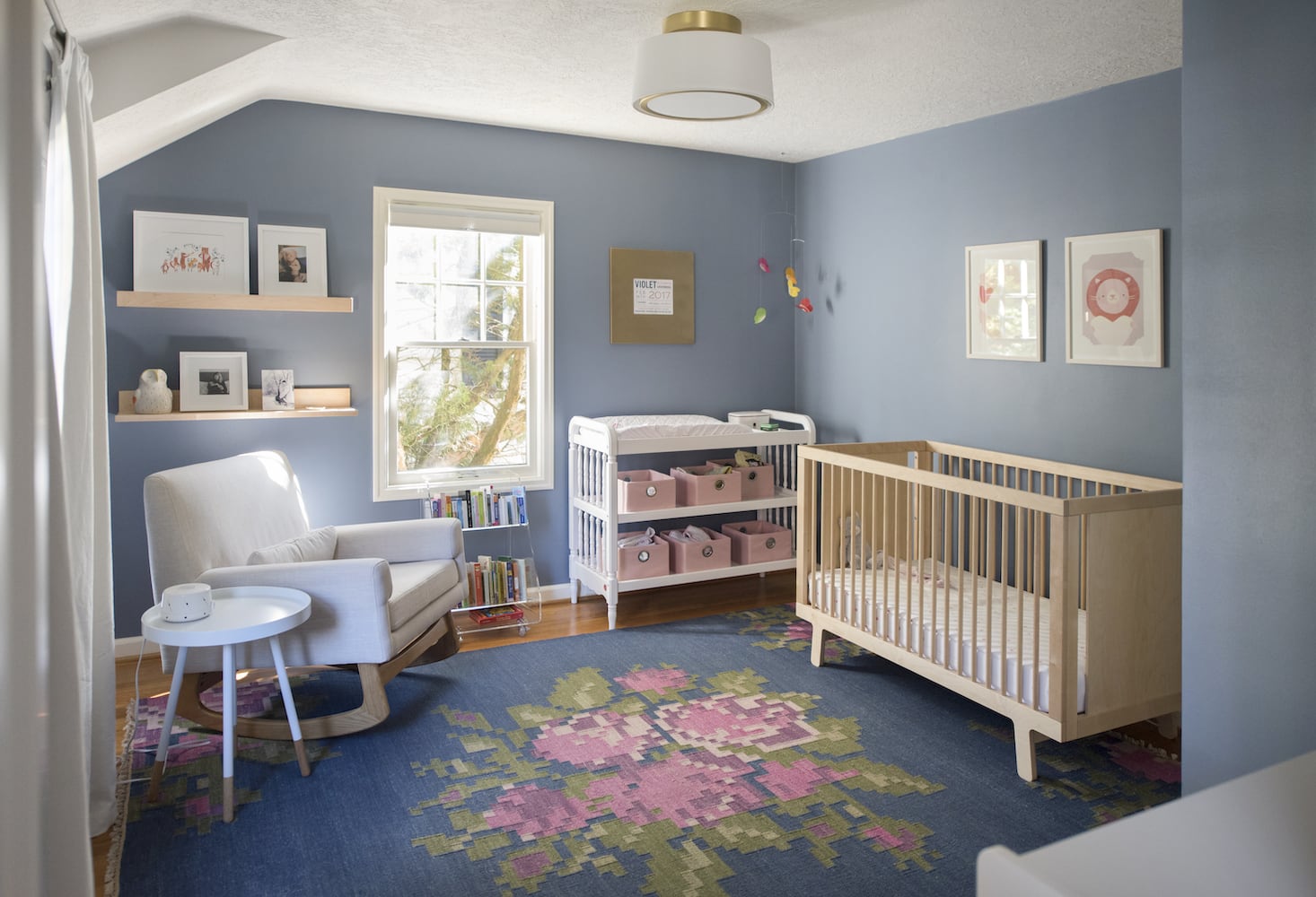 Children/kids room with pink, green and blue flower rug, rocking chair, baby crib