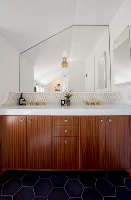 Dual bathroom sinks with gold fixtures, mirror that fits into slanted ceiling, mahogany