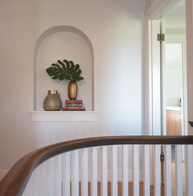 Upstairs stairway railing and landing with book/plant cathedral niche in white wall