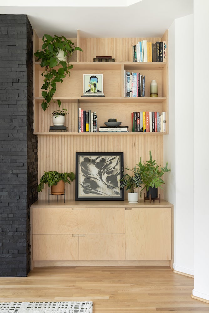 Birch bookshelves and lower cabinets with tambour paneling, plants, finger pulls