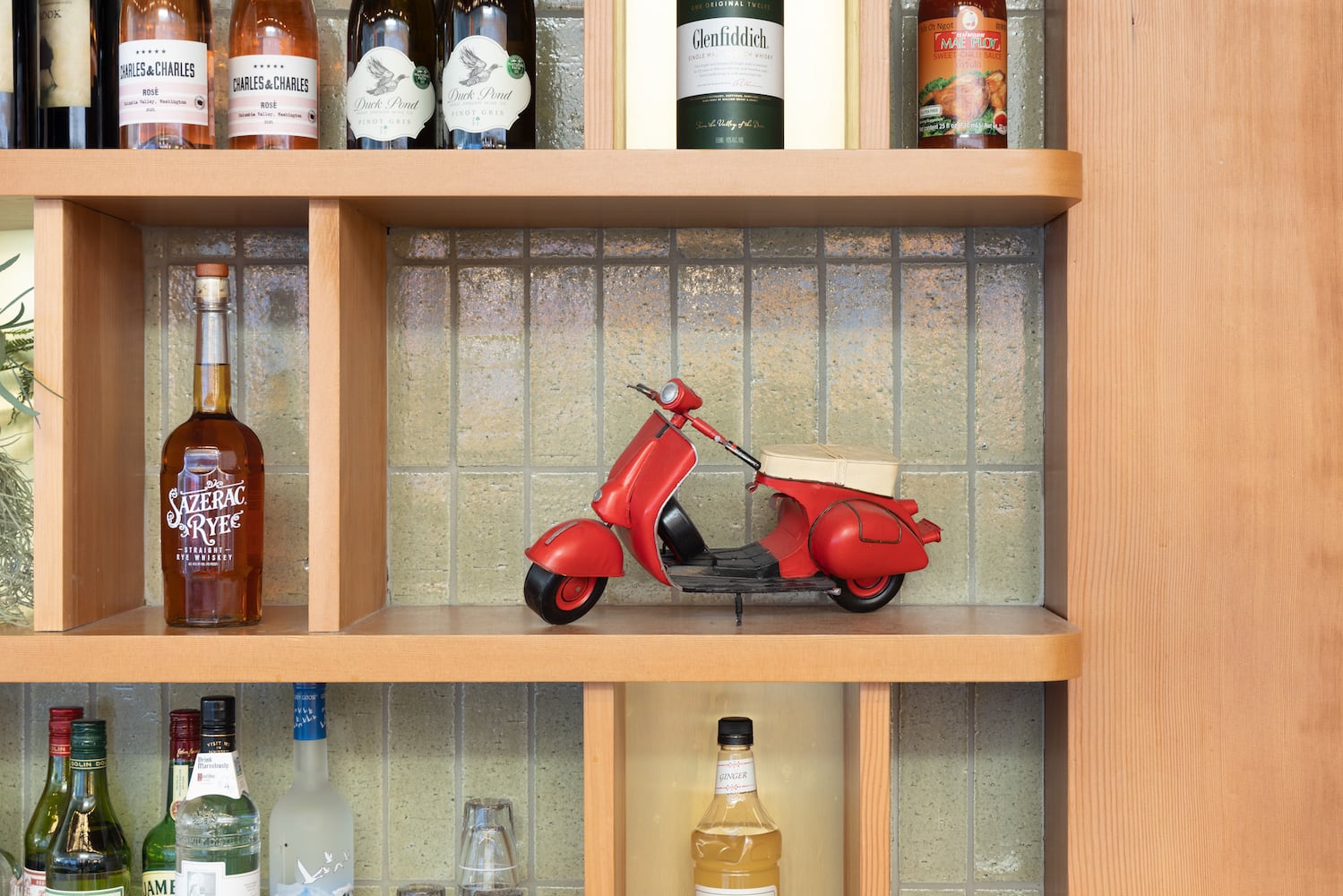 A miniature Vespa scooter sits among the cocktail ingredients behind the bar 
