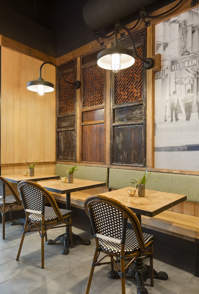 Matte black light fixtures hang above restaurant tables with reclaimed art on walls