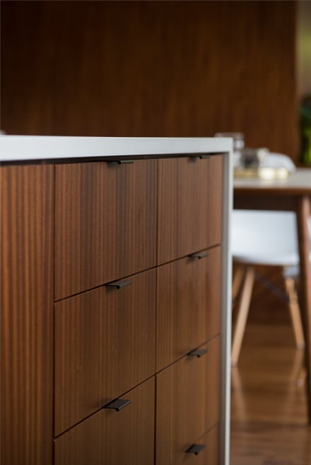 Detail of mahogany island cabinet drawers with matte black steel pulls
