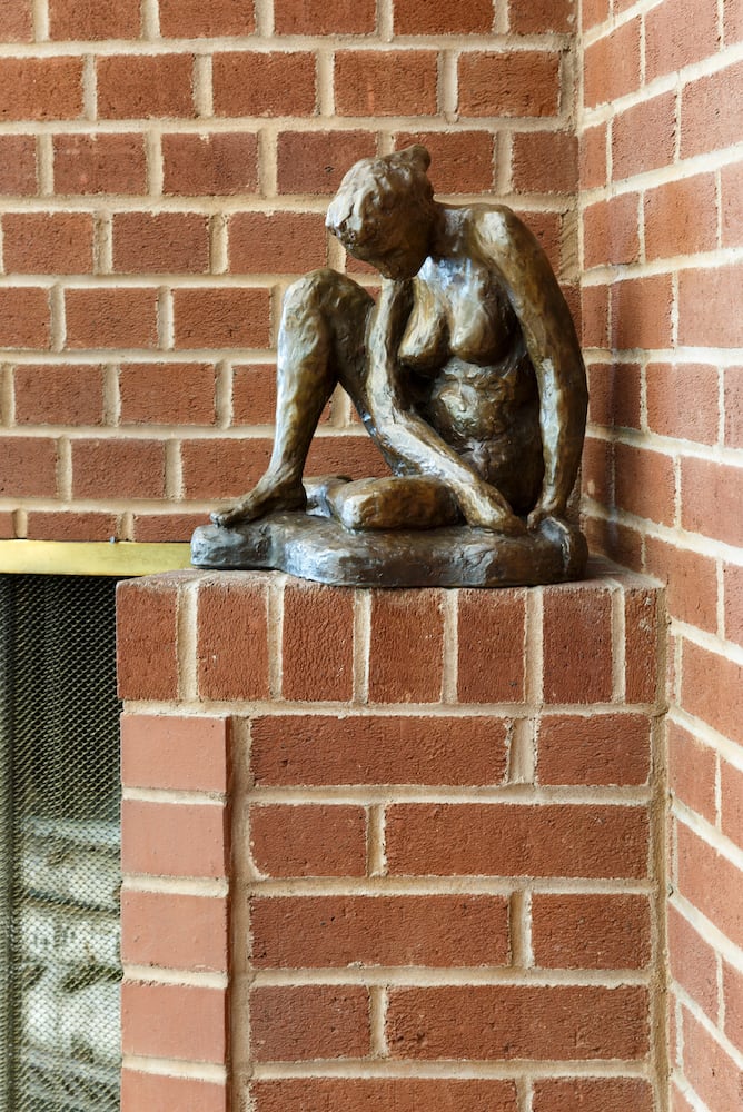Detail of circular brick fireplace with nude bronze sculpture