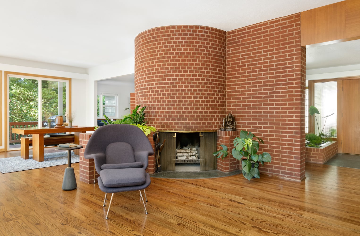 Full view of circular brick fireplace showing dining area and entry