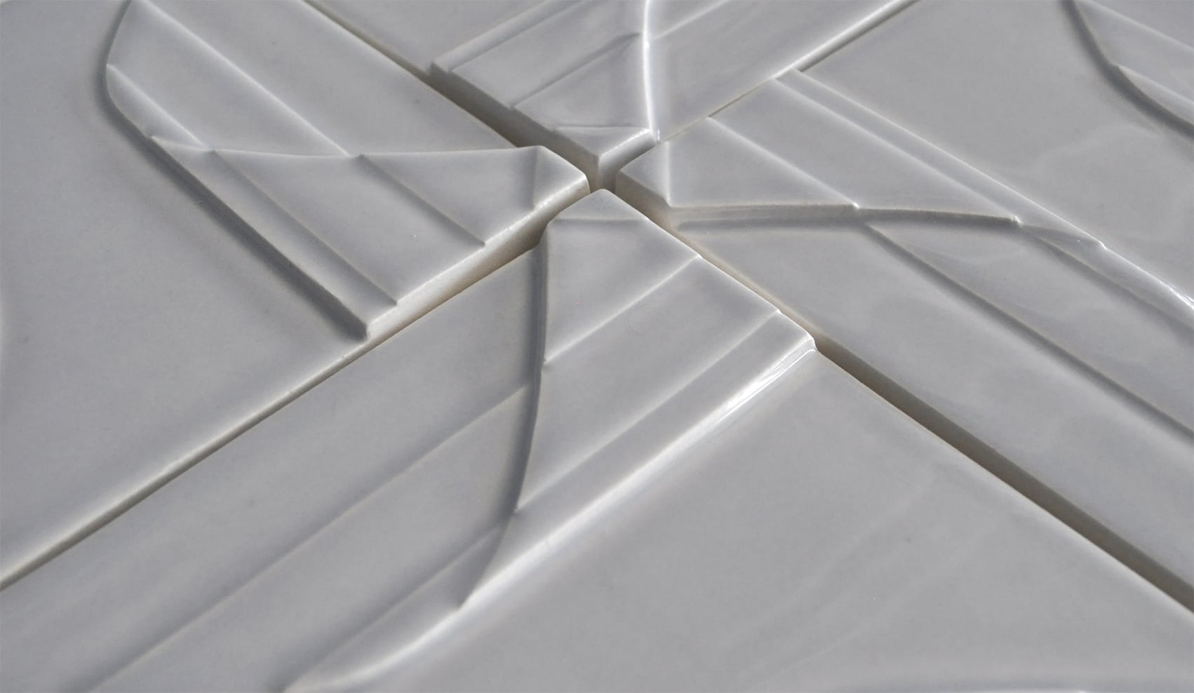 Four white square textured tiles placed edge to edge to create a pinwheel pattern