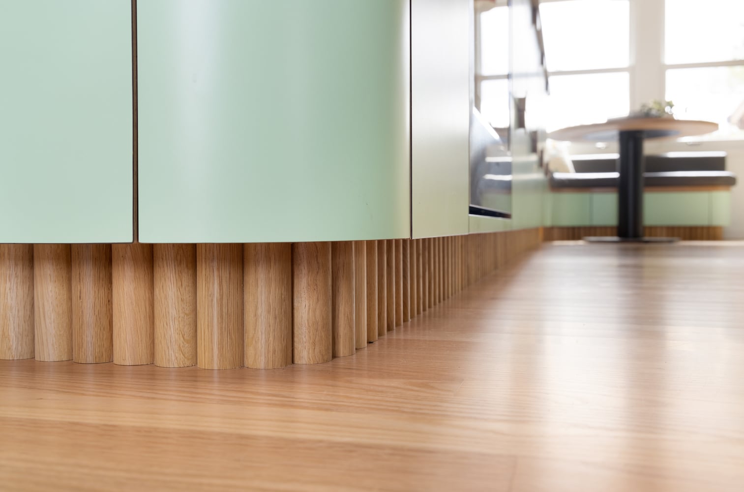 Detail of custom white oak tambour toe kick meeting natural wood floors at a curve