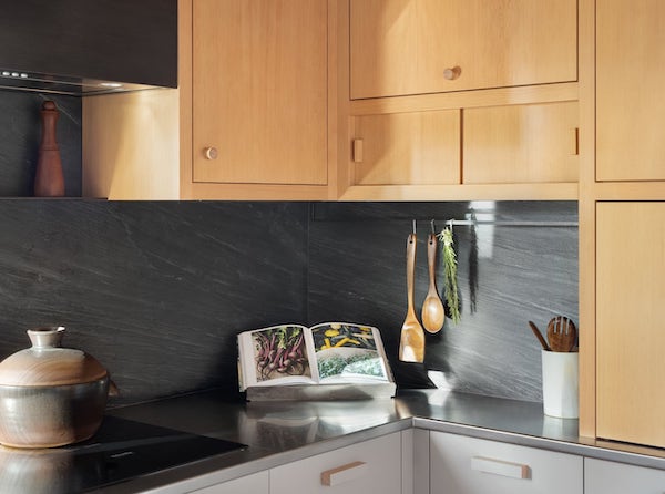Detail of stainless steel countertop with induction stovetop, utensil rack, cherry cabinets