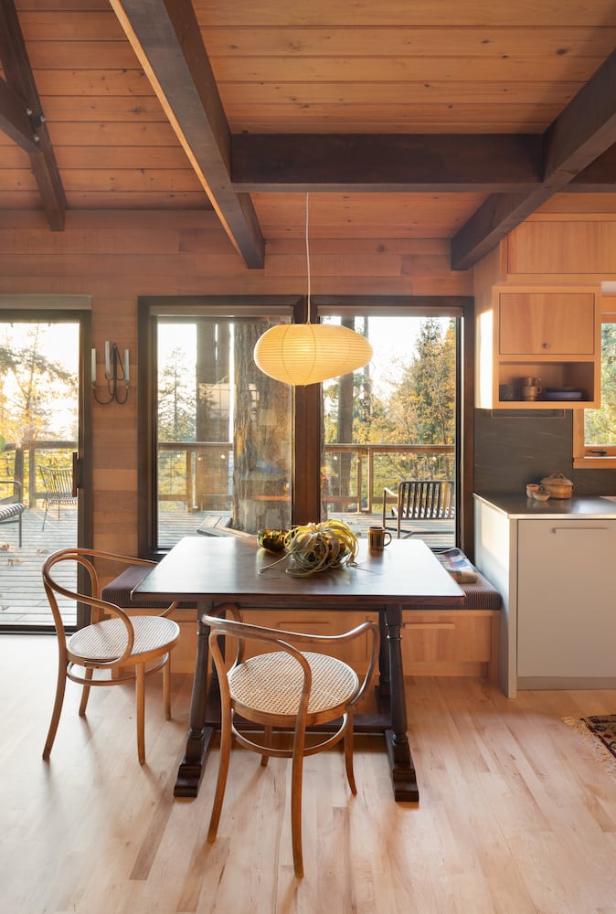 Beautiful wood beams sit atop a wood kitchen table for two, with natural light