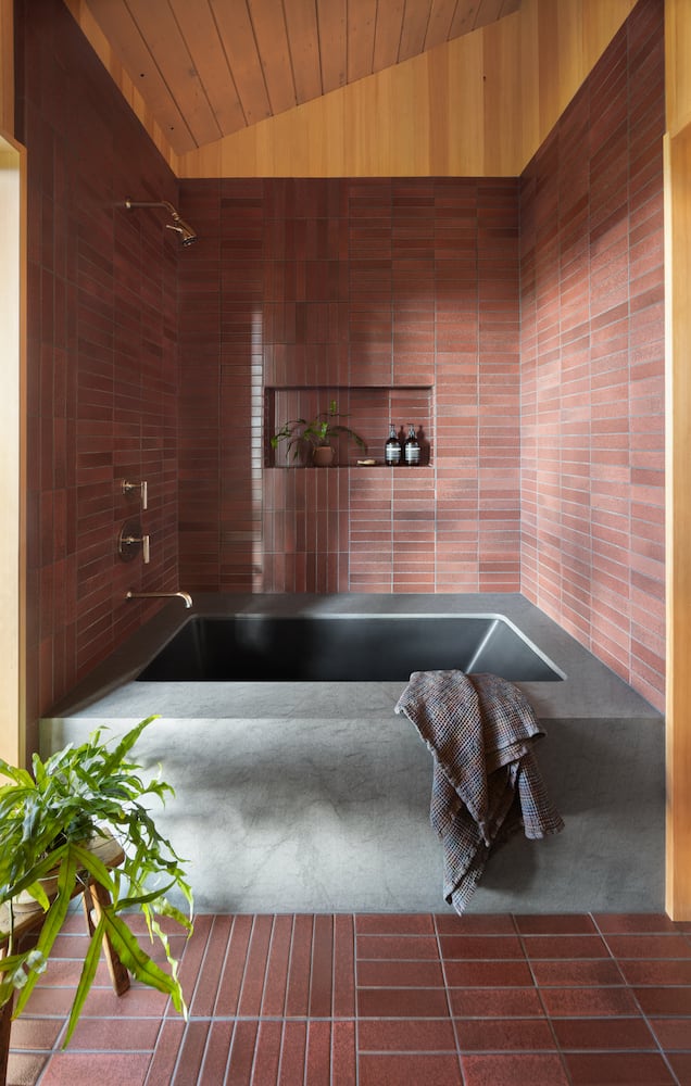 Geometric brick red modern tile design layout encases basaltina bathtub with plant