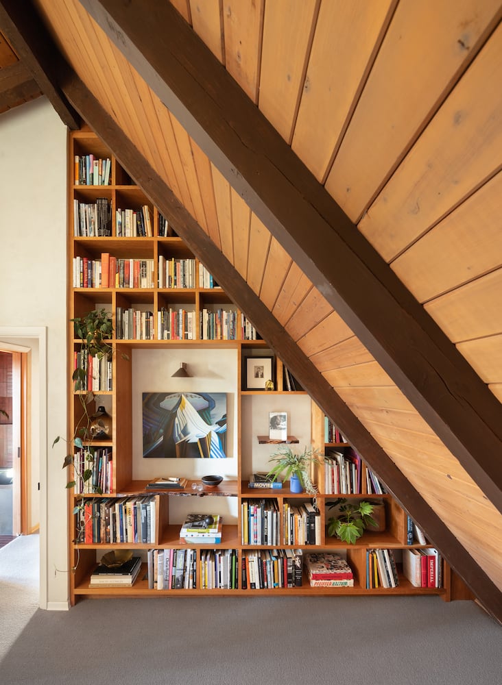 A-frame cabin remodel with angle ceiling creating a triangular custom bookshelf system
