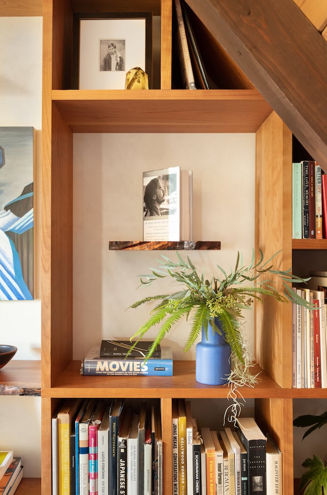 Plants and books about movies and film decorate custom bookshelves in this cabin