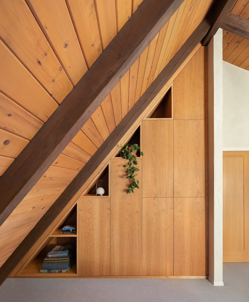 Upstairs of an a-frame cabin creates multiple triangles in custom wood shelving 