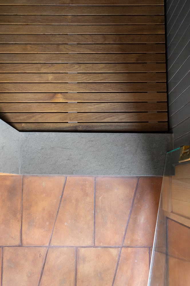 The seam between tierra geometric field tile, basaltina barrier and wood slat flooring