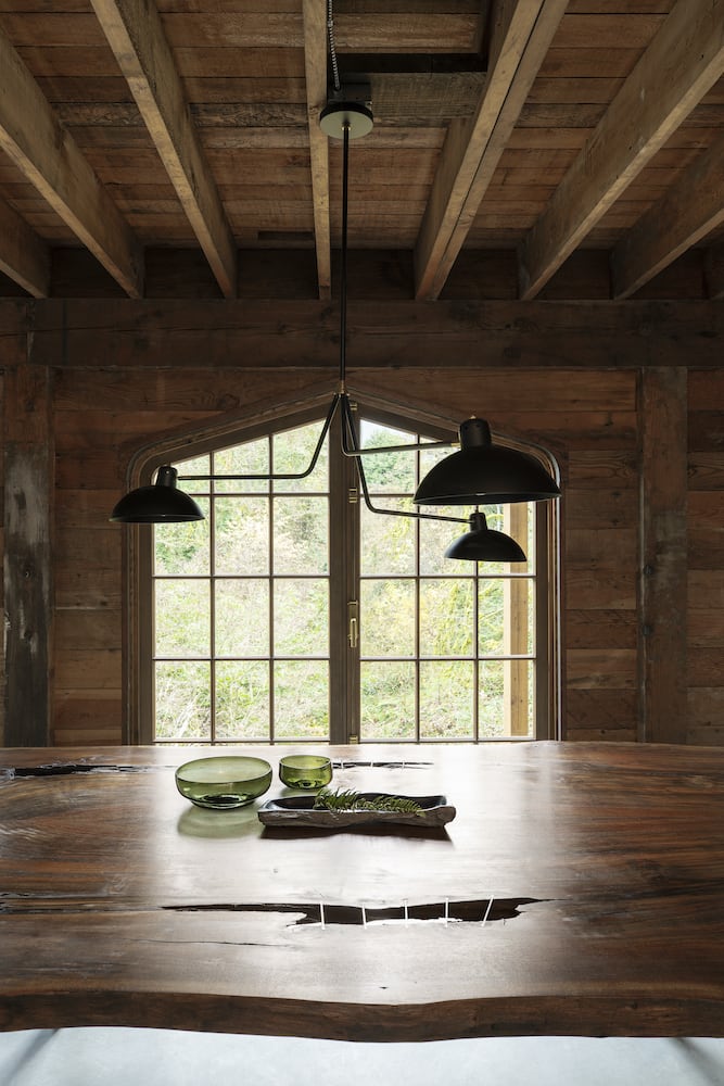 Allied Maker black chandelier over live edge wood table, exposed beams and framing