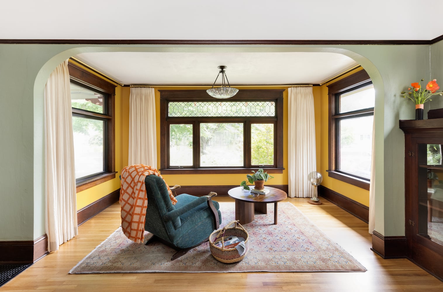 Warm reading corner with modern walnut coffee table, leaded glass windows, earth tones