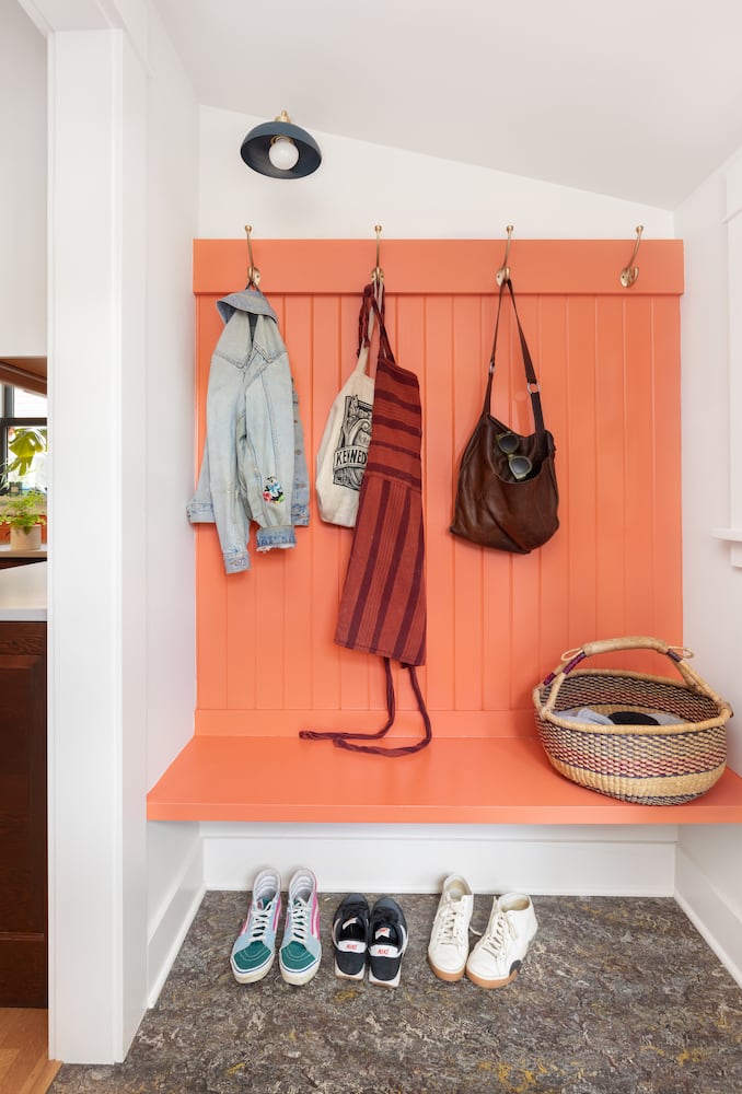 Custom mudroom with orange Benjamin Moore paint and sconce from Schoolhouse Electric
