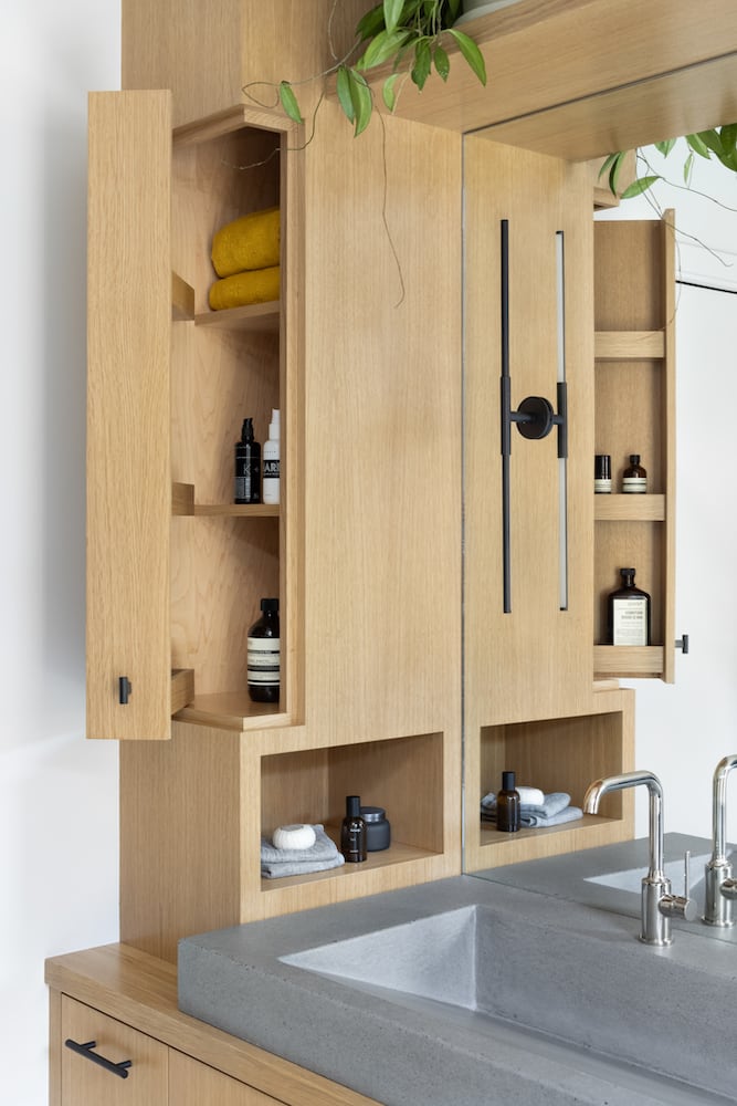 Hayhurst Bath: White oak cabinet with built-in niche, custom woodwork door revealing extra storage