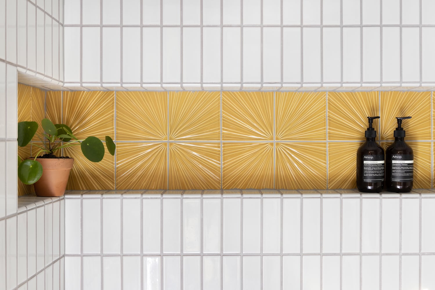 Detail of custom shower niche with Clayahus sunburst yellow pattern, bullnose tile
