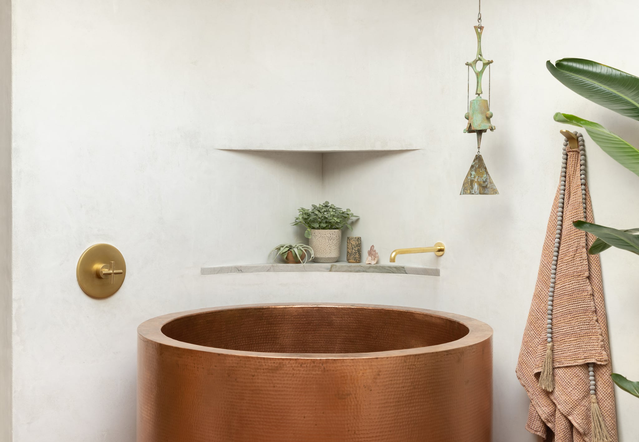 Copper soaking tub with gold filler built into white wall, unique corner plant niche