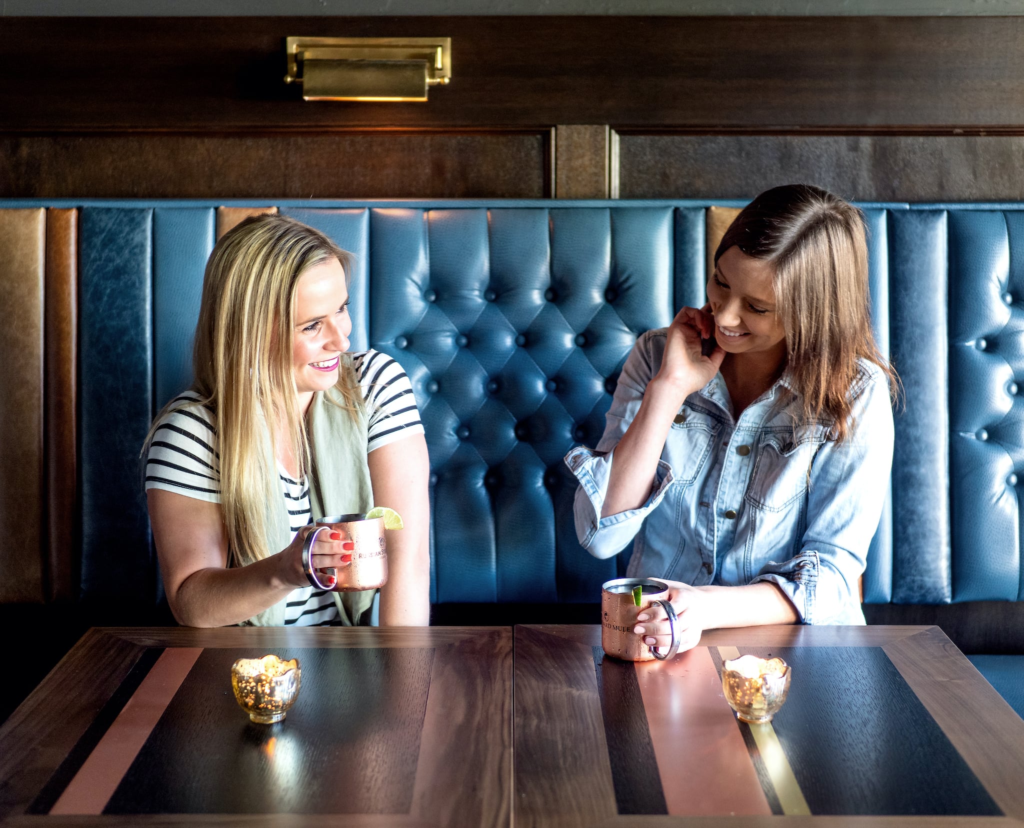 Restaurant patrons in tufted leather booth with drinks, hospitality interior design