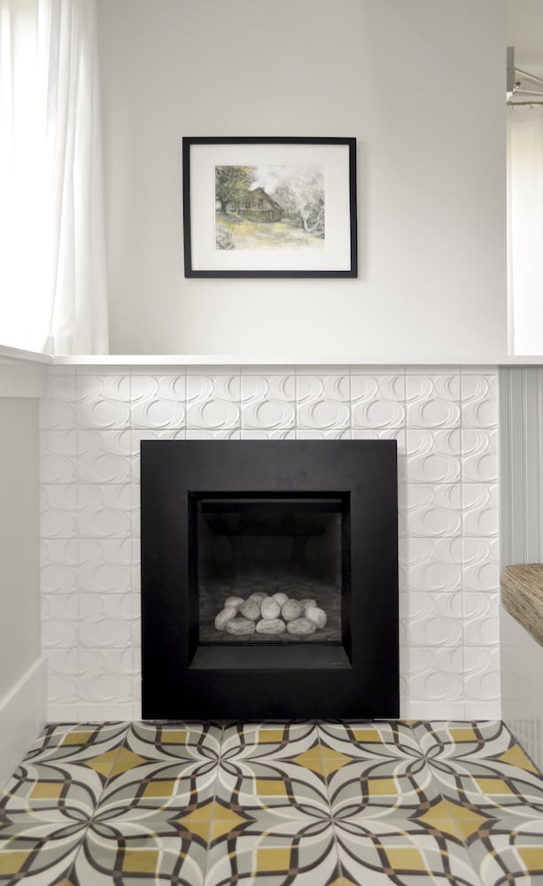 Straight-ahead shot of black gas fireplace surrounded with glazed white tile