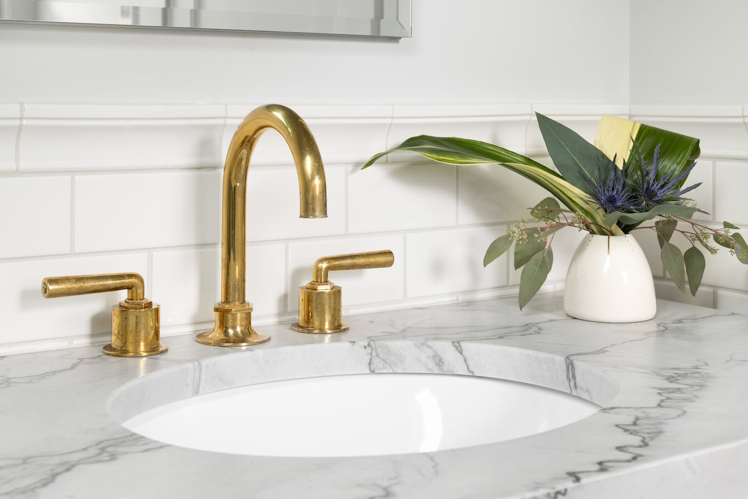 Powder room sink with polished gold faucet, quartz counter, white tile backsplash