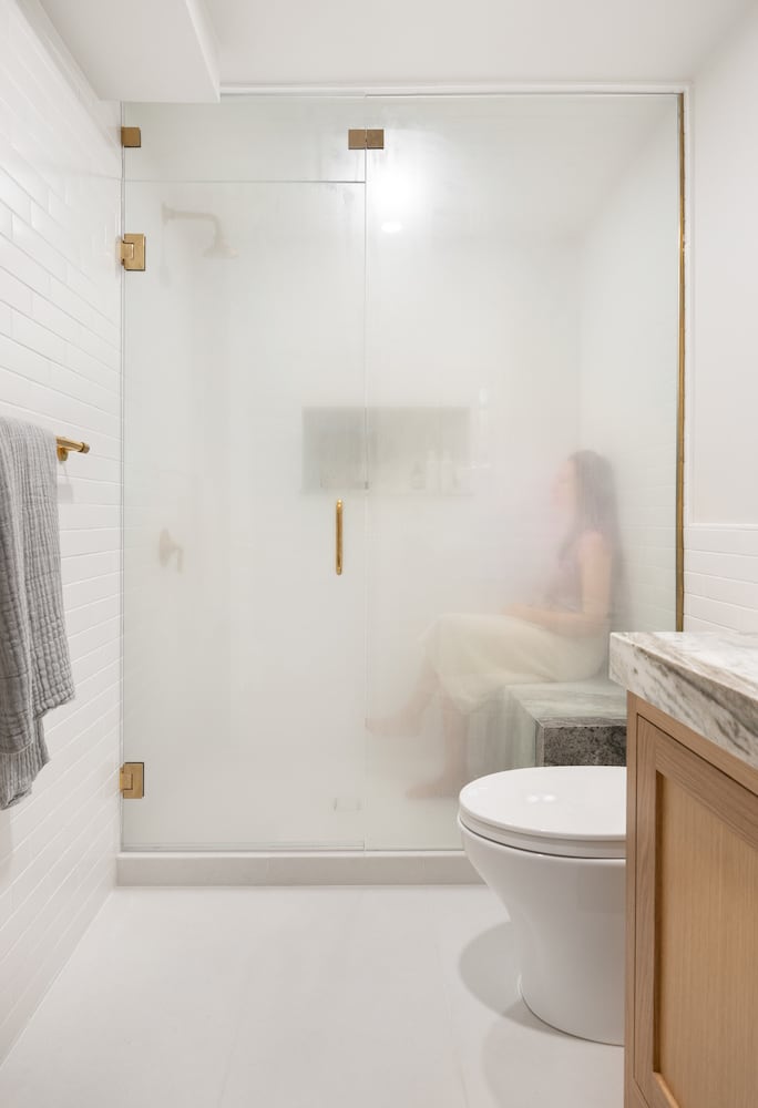 Person relaxing on a custom marble bench in steam shower bathroom design 