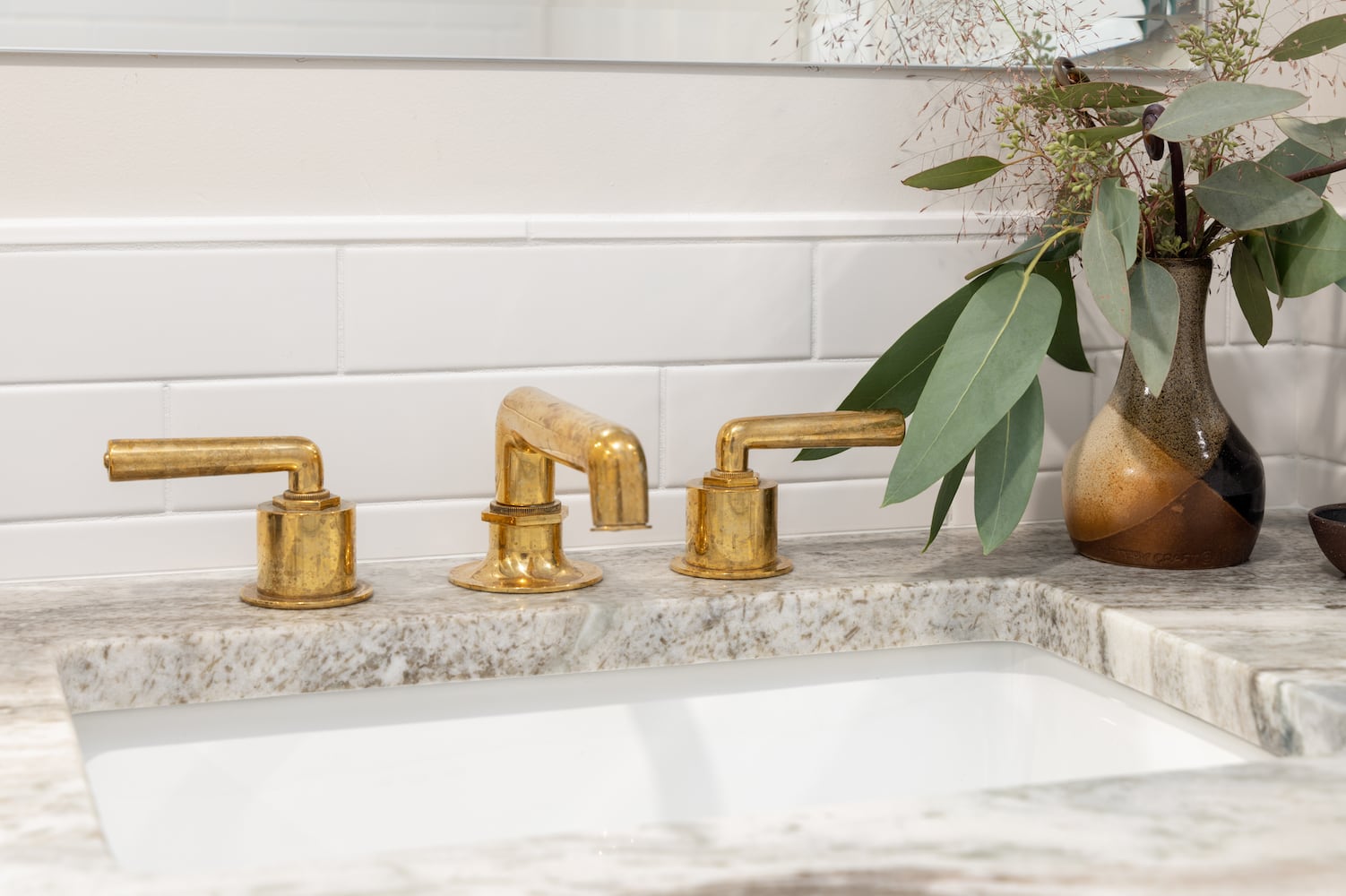 Close-up of living finish bathroom sink with burnished brass faucet and marble counter