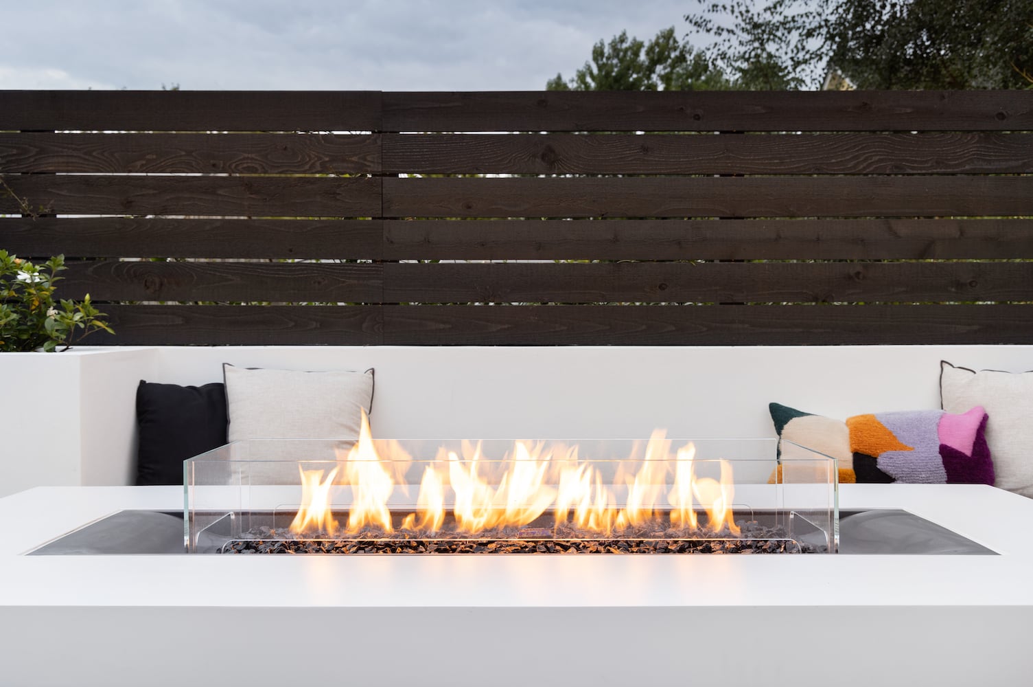 Backyard gas fireplace with custom couch pillows and benches and private fencing