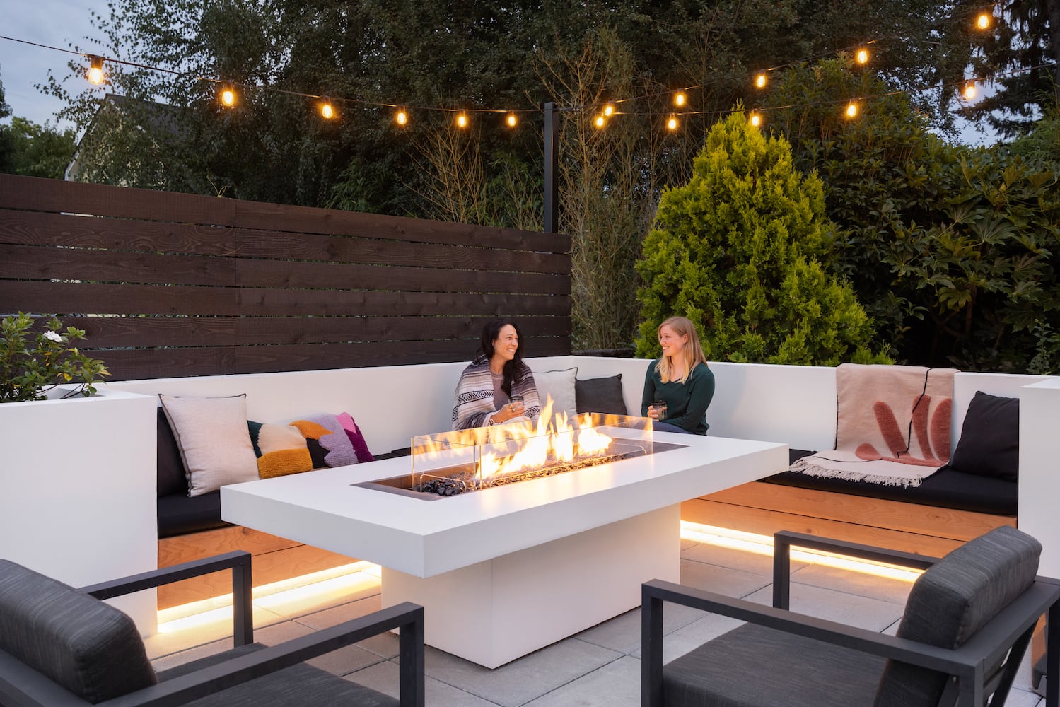 Interior designers enjoy an outdoor fireplace with string lights, custom couch