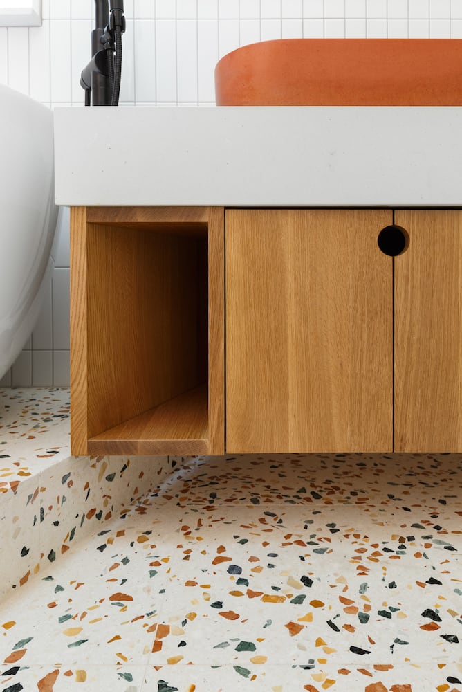 Detail of white oak cabinet with colored terrazzo floor in bathroom remodel