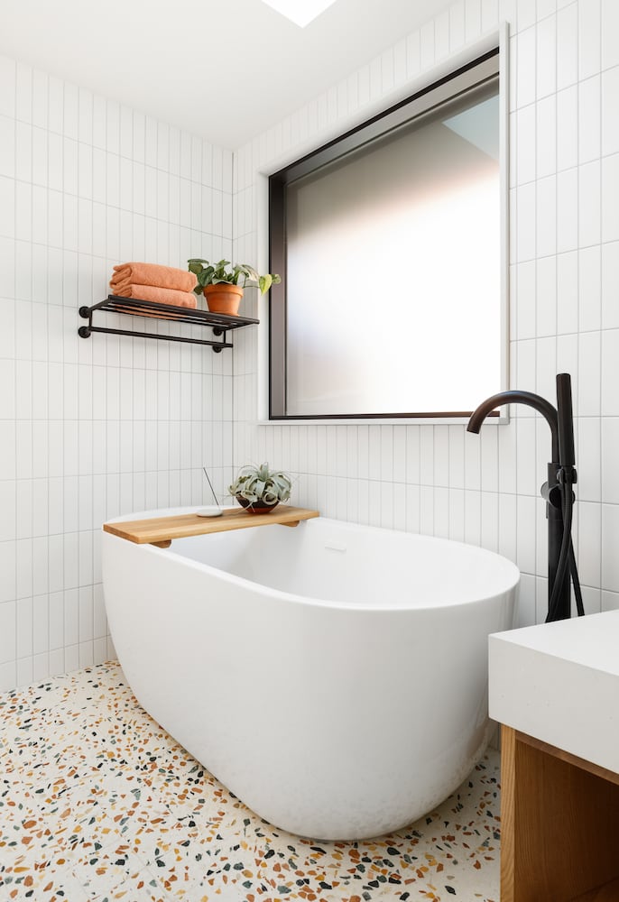 Freestanding bathtub with black floor mounted tub filler, terrazzo floors