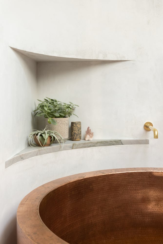 Corner plant niche is expertly renovated into existing wall above copper soaking tub
