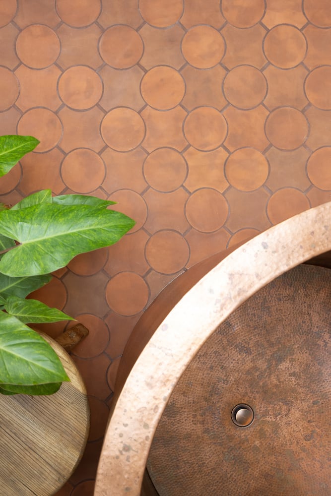 Circular interplay among the earth tones of tierra floor tile and copper soaking bathtub