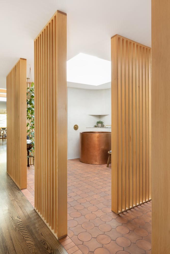 A series of vertical wood slats frame the open decor and vibe of this atrium home spa