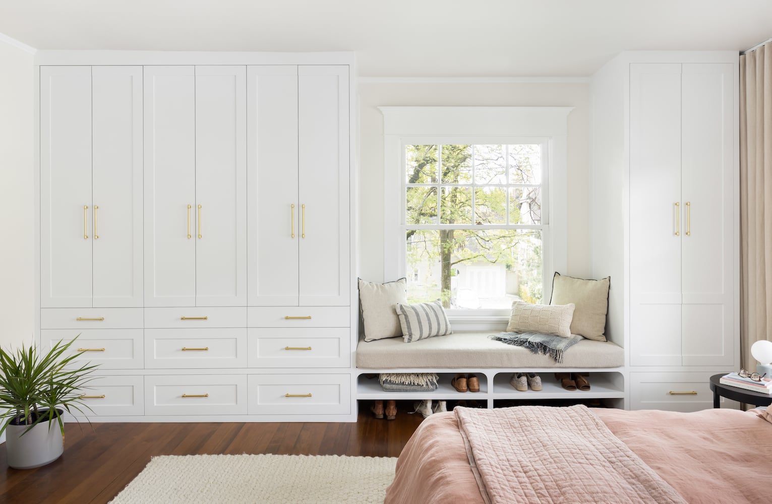 Custom bedroom cabinetry painted white with gold cabinet pulls for doors and drawers
