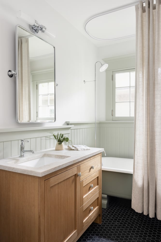 Bathroom sink with vanity sconce and oval mirror, hand-selected countertop, wood cabinet
