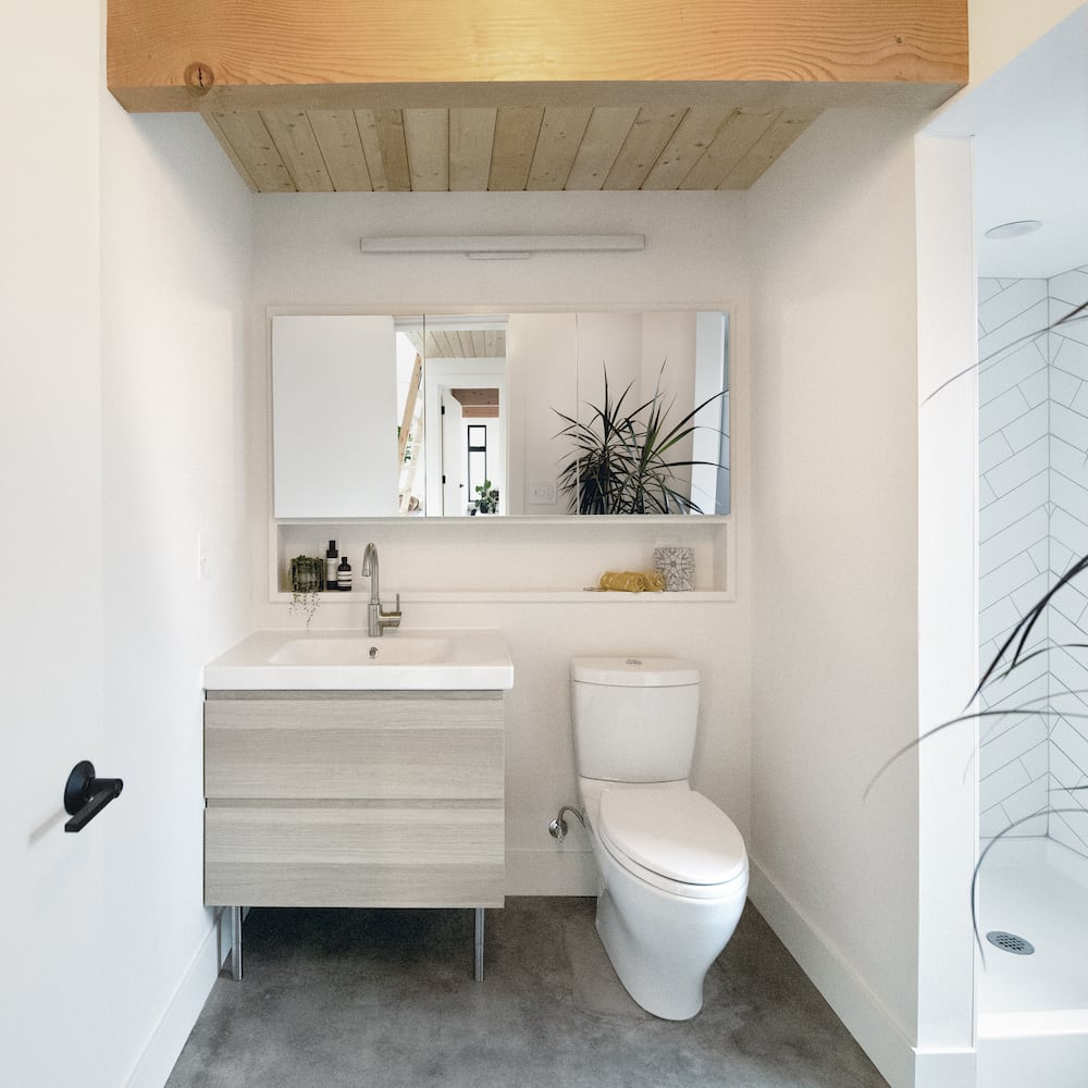 Modern ADU bathroom with tongue-in-groove pine ceilings, above-sink niche, toilet