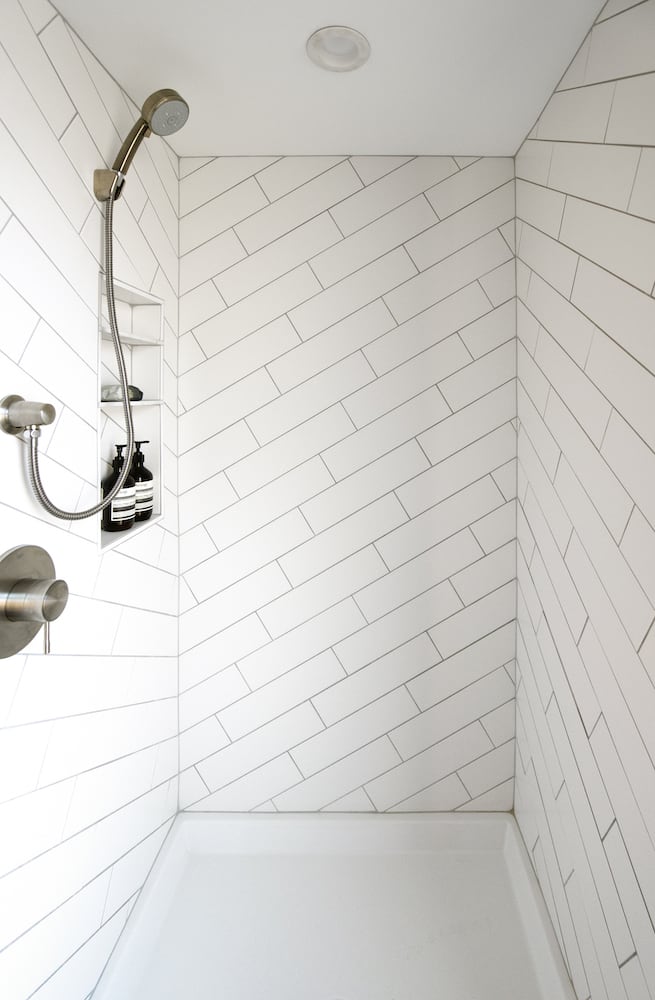 White shower with diagonally placed rectangular tile, polished silver fixtures, niche