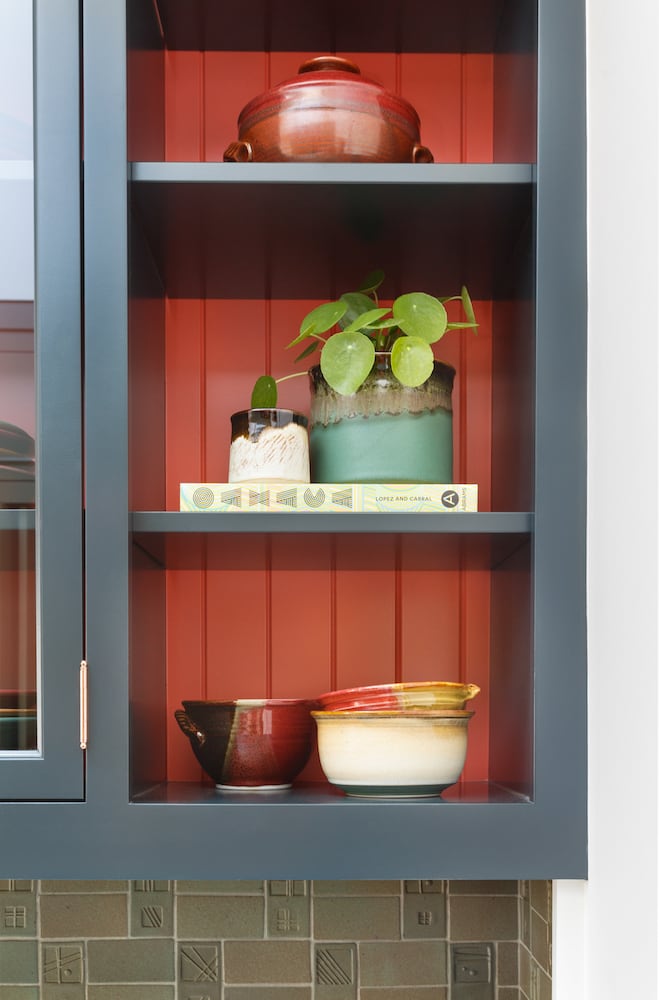 Kitchen painted cabinet detail with open shelving, plant and ceramics