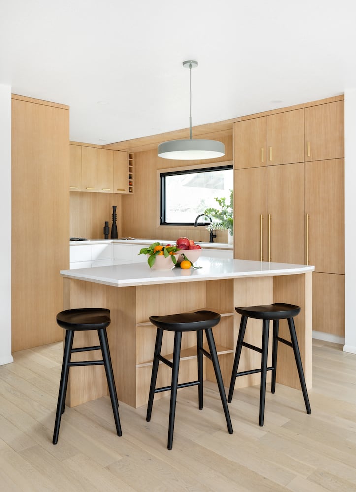 Modern light wood kitchen with pentagon island, white countertops, green pendant