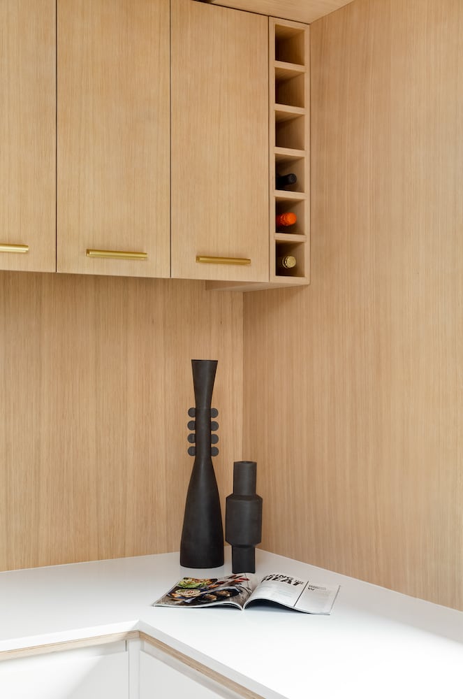 Modern light wood kitchen, wine storage, white counters, wood backsplash