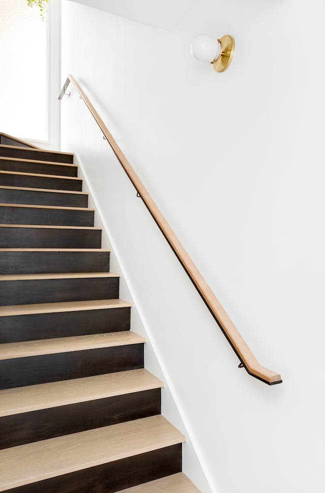 Modern stairwell with steel risers and custom wood and steel handrail, wall sconce