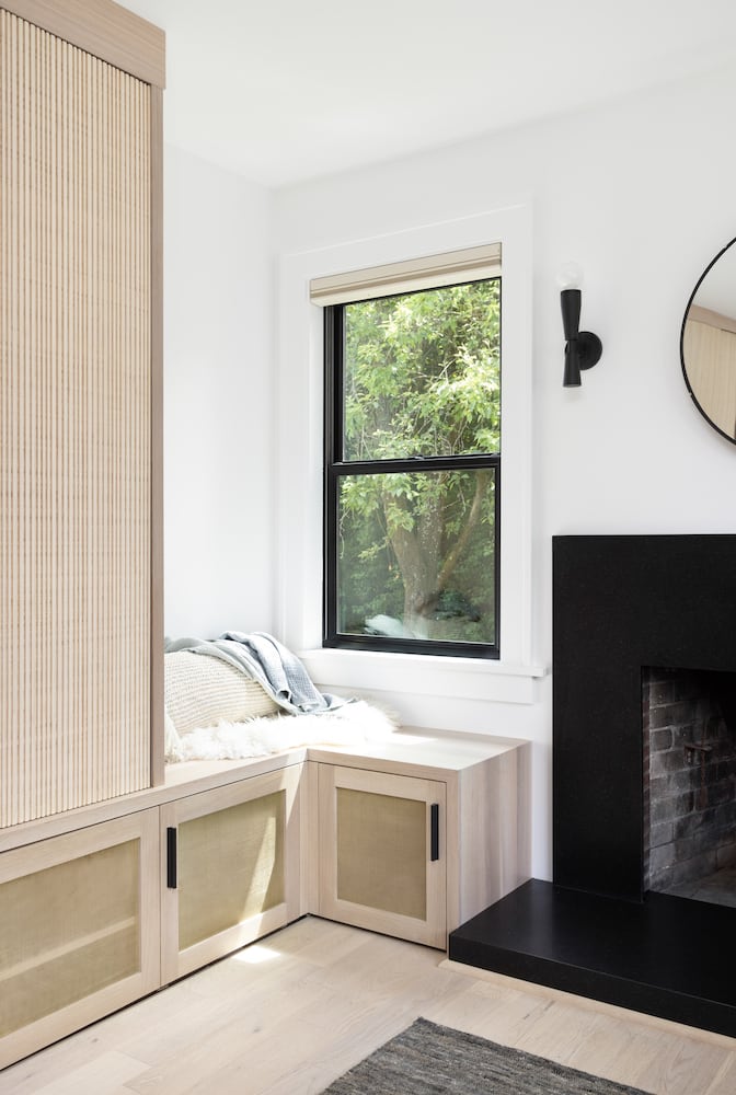 Custom white oak built-in reading bench window alongside black fireplace