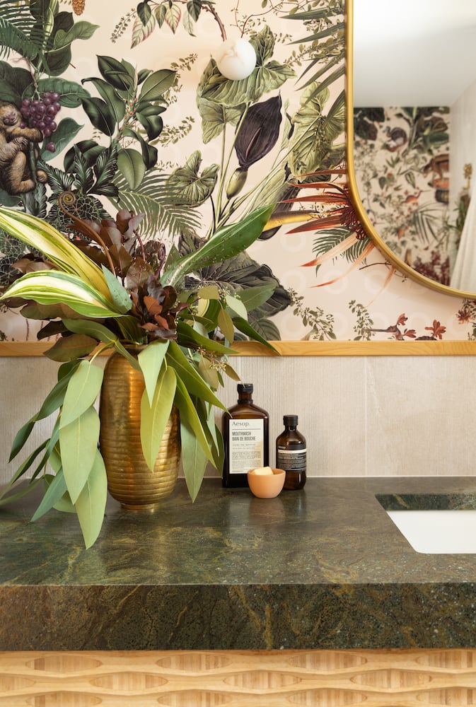 Plants and luxury cleaning products sit near the renovated sink atop green granite