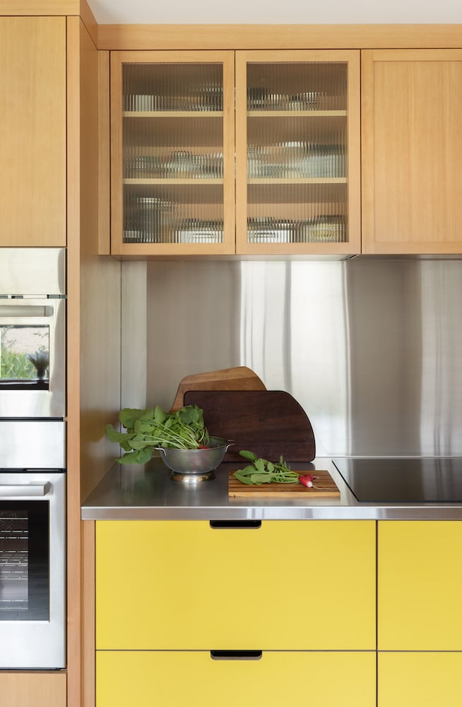 Fresh farm vegetables sit near induction cooktop, with stainless counter and backsplash
